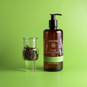 Apivita Tonic Mountain Tea Shower Gel alongside a towel