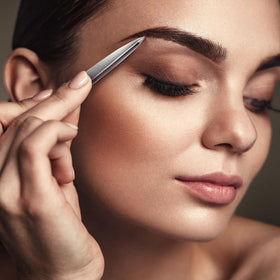By MILLY Pointed Tweezers on a vanity alongside other beauty tools