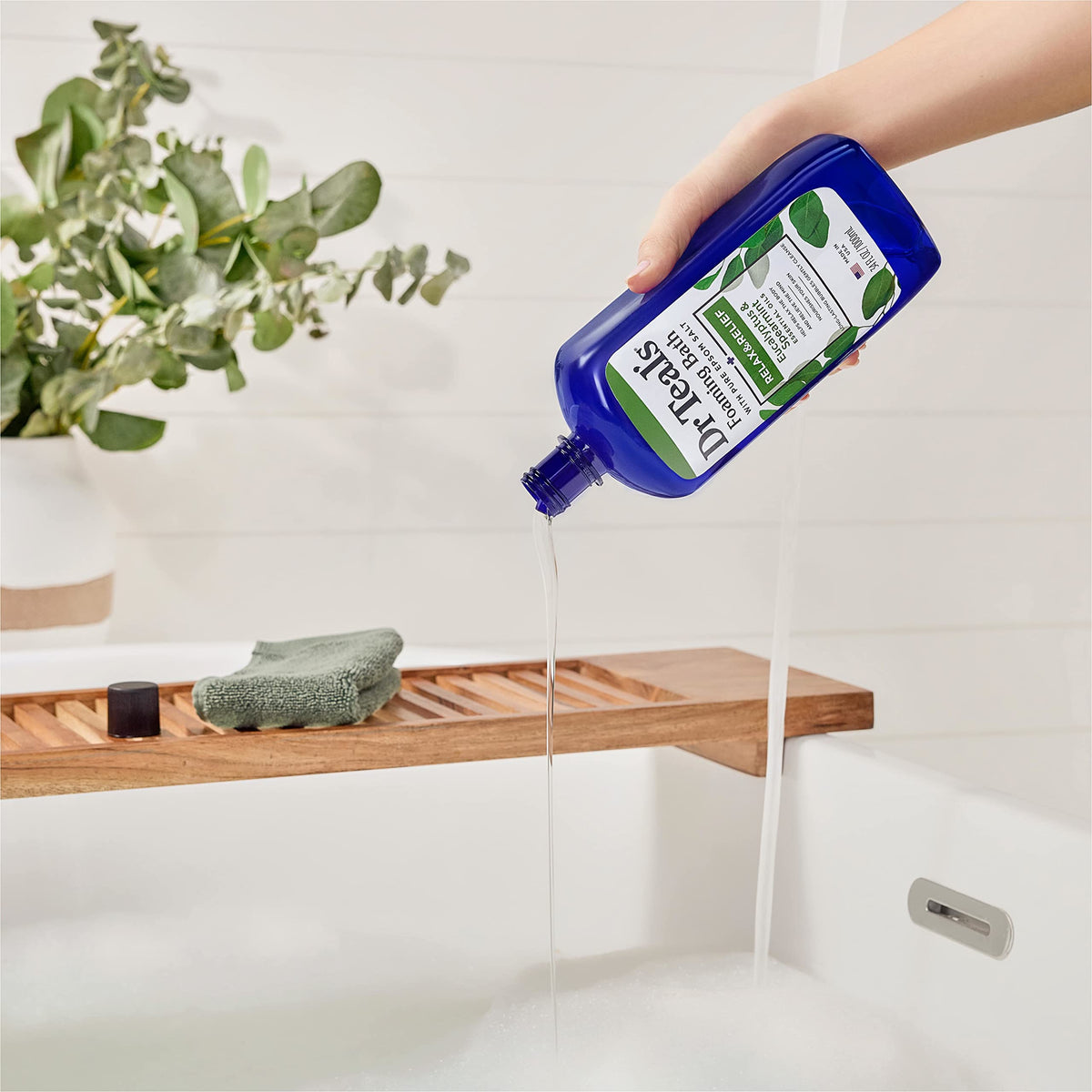 Dr Teal's Foaming Bath bottle with bubbles in a bathtub