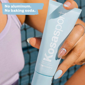 Kosas Chemistry AHA Serum Deodorant with fresh flowers background