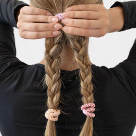 L. Erickson soft peach ponytail holder in a hand