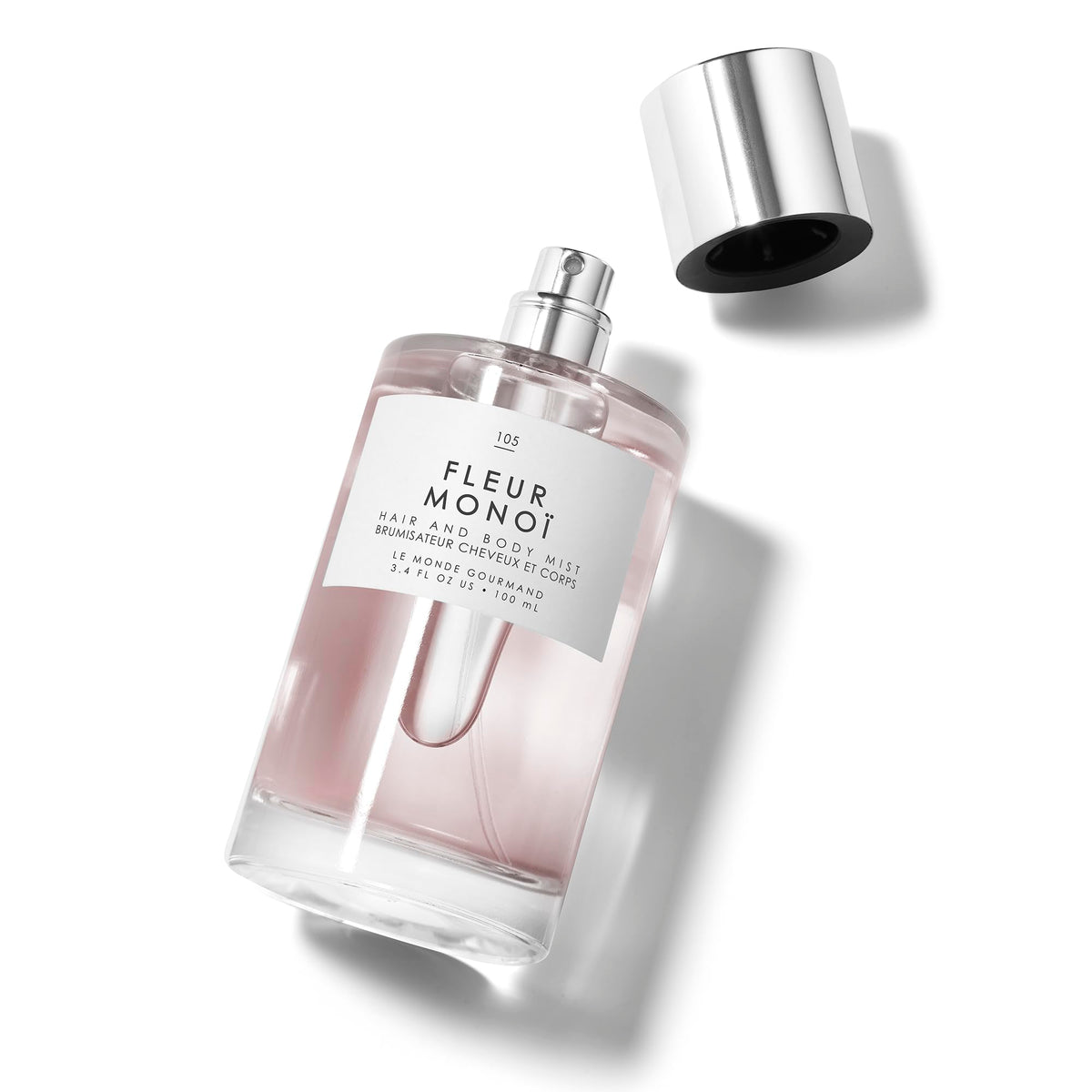 Le Monde Gourmand Fleur Monoi Hair & Body Mist 100ml bottle with floral background