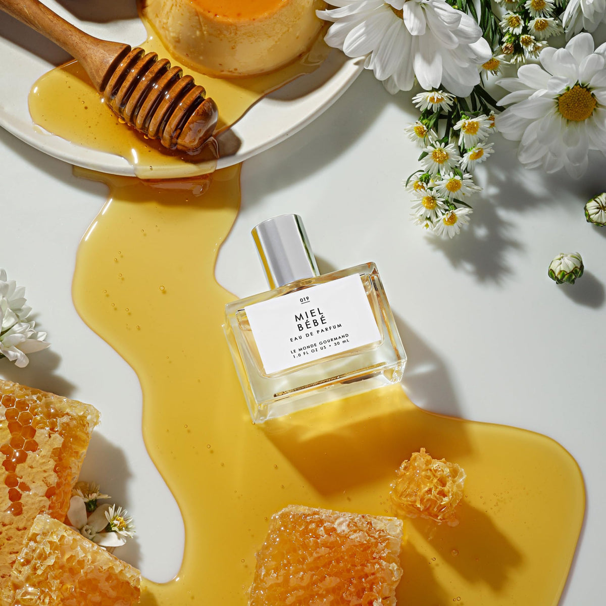 Le Monde Gourmand Miel Bébé Eau de Parfum on a vanity with flowers