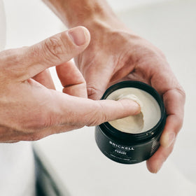 Lifestyle shot of man using Brickell Men's Hair Styling Clay Pomade