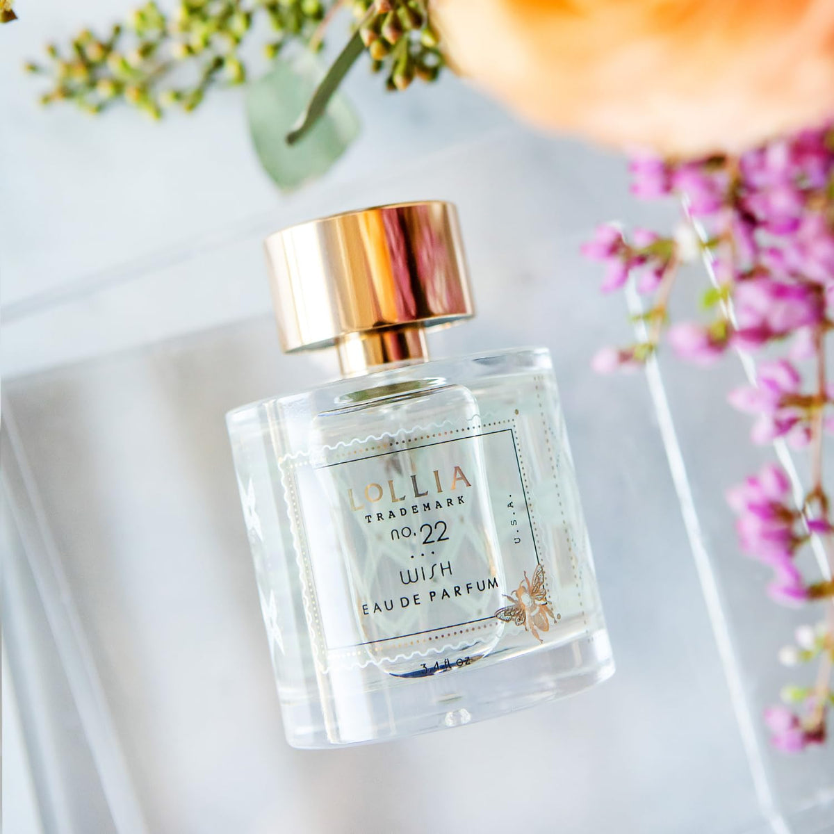 LOLLIA Wish Eau de Parfum bottle on a vanity with flowers