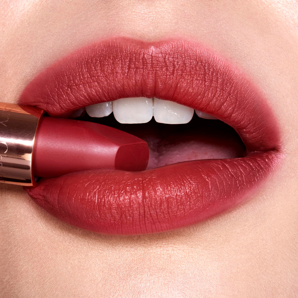 Model applying Charlotte Tilbury Matte Revolution Lipstick in a makeup setting