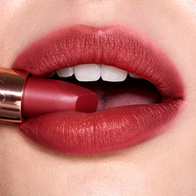 Model applying Charlotte Tilbury Matte Revolution Lipstick in a makeup setting