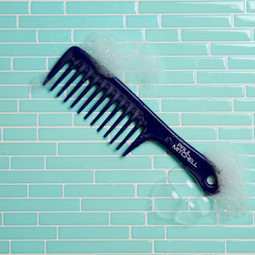 Paul Mitchell Detangler Comb on a bathroom counter with hair products